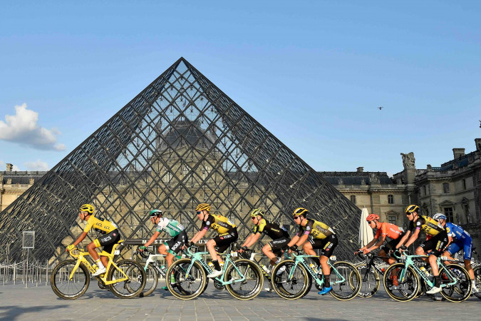 TOPSHOT - Colombia's Egan Bernal (L) of Team Ineos wears the overall leader's yellow jersey as he passes with the pack past the pyramid of The Louvre Museum designed by Ieoh Ming Pei during the twenty-first and final stage of the 106th edition of the Tour de France cycling race between Rambouillet and Paris Champs-Elysses in Paris on July 28, 2019. (Photo by Julien DE ROSA / POOL / AFP) / RESTRICTED TO EDITORIAL USE - MANDATORY MENTION OF THE ARTIST UPON PUBLICATION - TO ILLUSTRATE THE EVENT AS SPECIFIED IN THE CAPTION        (Photo credit should read JULIEN DE ROSA/AFP via Getty Images)